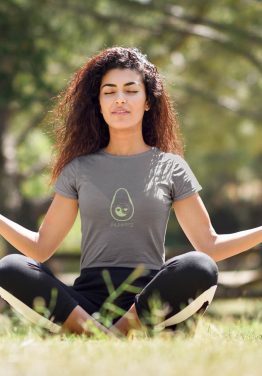 avocado-always-t-shirt-worn-by-a-young-woman-with-curly-hair-meditating-in-the-park